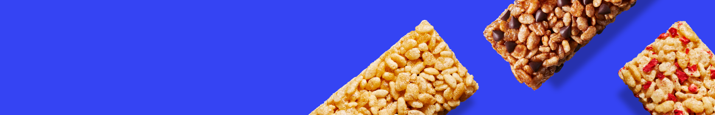 Three crispy squares on a vibrant blue background. The first is plain, the second has chocolate chips, and the third includes red strawberry pieces.