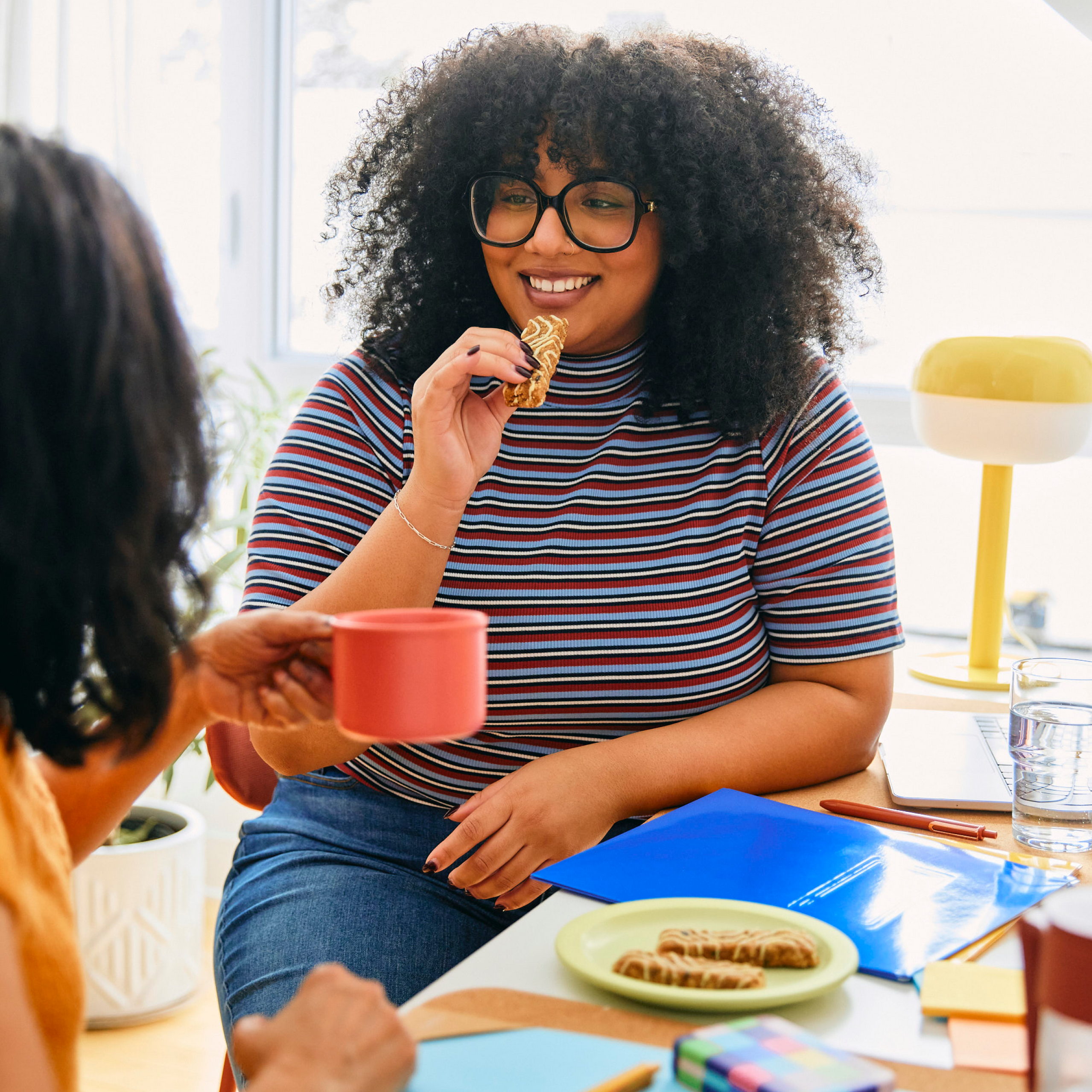 A woman eating  a Mornings Bar with a friend