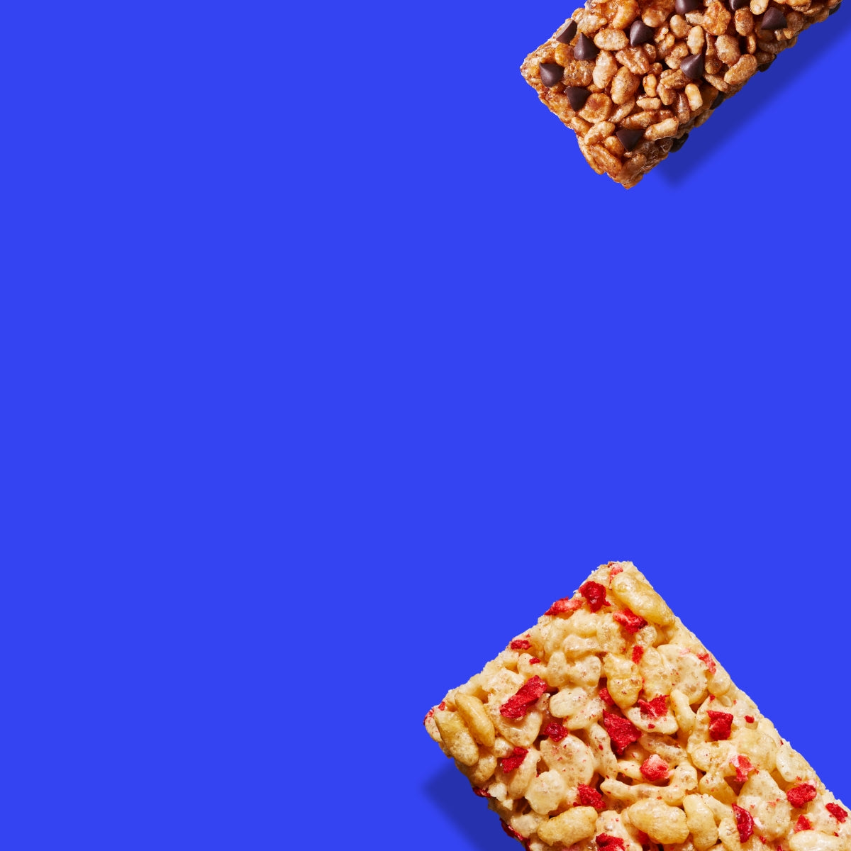 A chocolate chip and strawberry rice crispy squares are placed on opposite corners of a blue square