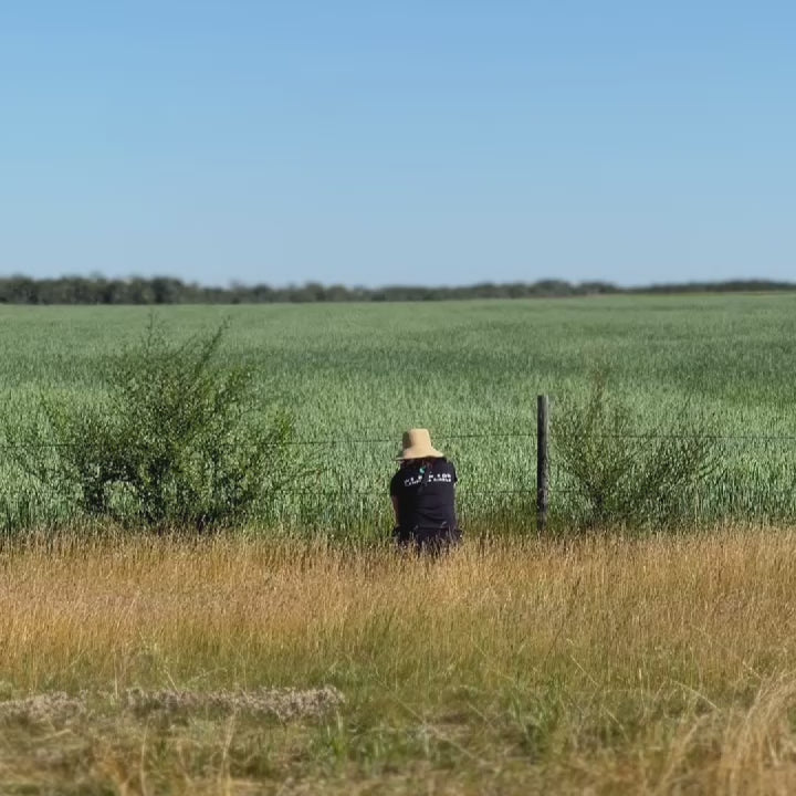 a woman wearing a hat sitting in an oat field