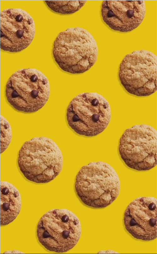 Chocolate chip cookies arranged in a neat pattern on a vibrant yellow background. Some cookies feature chocolate chips, adding variety and playfulness.